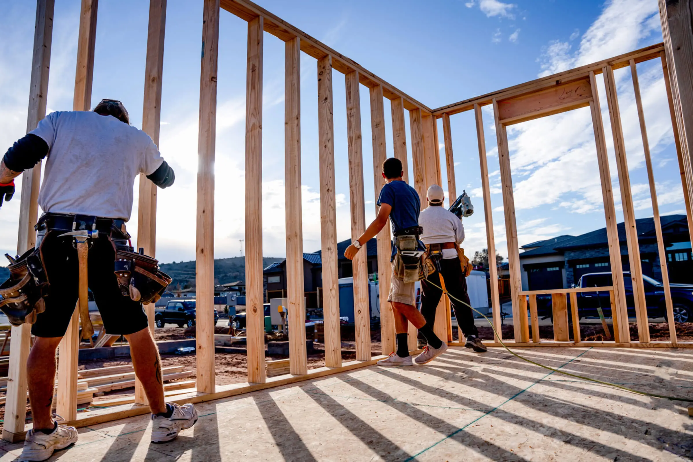 Construction workers building wooden house frame.